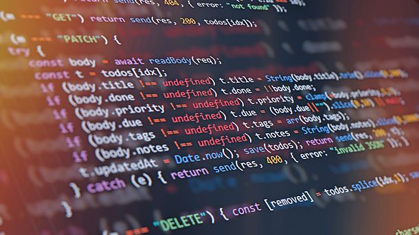 Close-up of computer screen showing colorful programming code lines with syntax highlighting and blurred light reflections. Abstract background representing software development, AI programming, machine learning, cybersecurity, and modern technology innovation. Perfect for illustrating digital transformation and data science concepts.