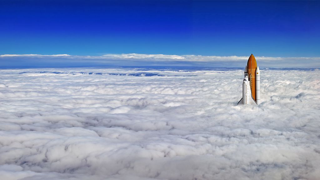 A rocket sticking out of a blanket of cloud.
