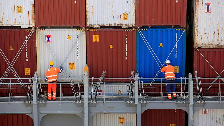 Zwei Mitarbeitende sichern Container für den Seetransport. 