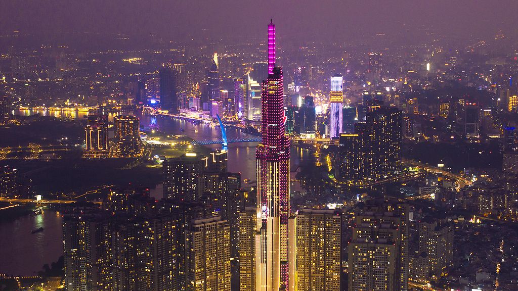 Luftaufnahme des Wolkenkratzers „Landmark 81“ und der leuchtenden Skyline von Vietnams Metropole Ho-Chi-Minh-Stadt bei Nacht.