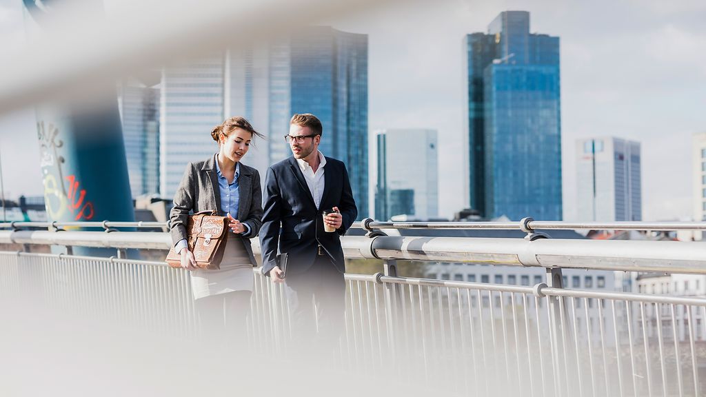 Young business couple walking on bridge, talking
