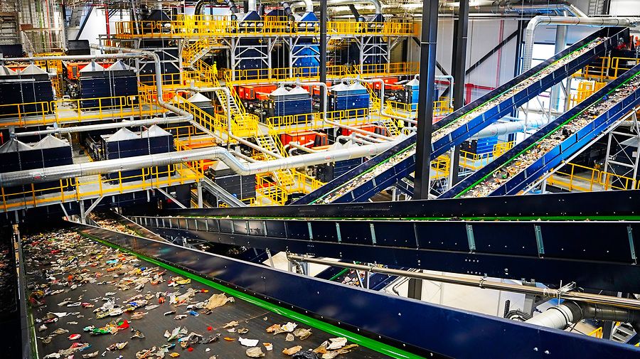 Industrielle Abfallsortieranlage mit mehreren Förderbändern in Blau und Grün, die in verschiedenen Ebenen angeordnet sind