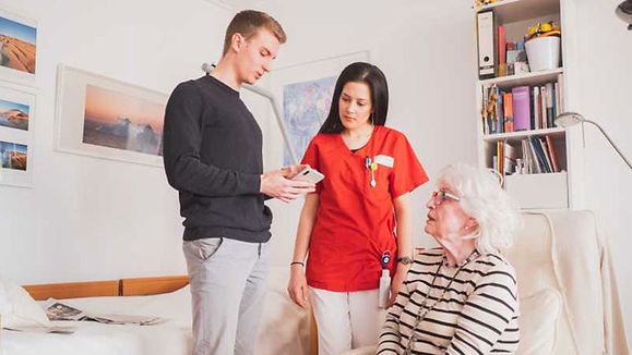 Young man is showing patient and nurse the new app on mobile phone.