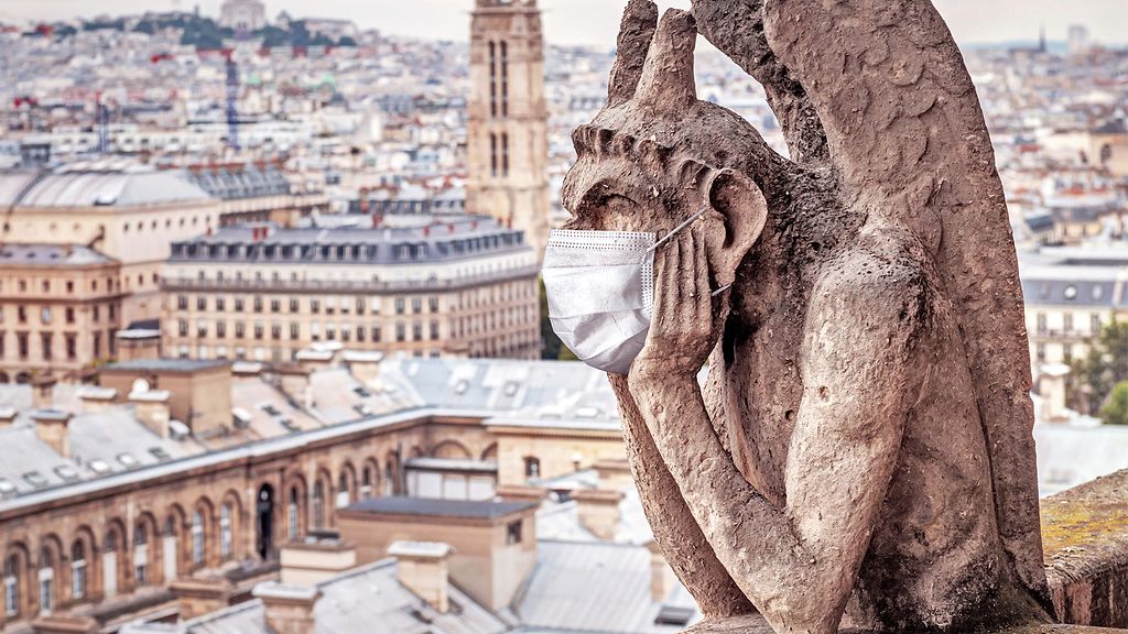 COVID-19 coronavirus in France, medical mask on gargoyle of Notre Dame in Paris. Tourist landmarks closed due to corona virus outbreak. | © GettyImages/scaliger/Viacheslav Lopatin