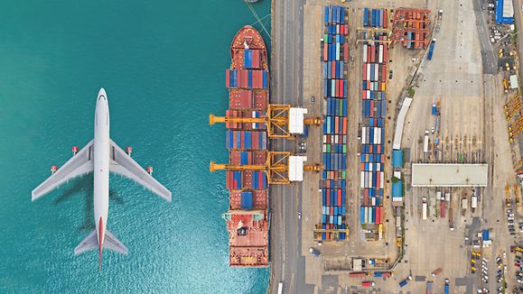 Aerial top view Airplane fly over Container cargo ship at Terminal commercial port for business logistics, import export, shipping or freight transportation.