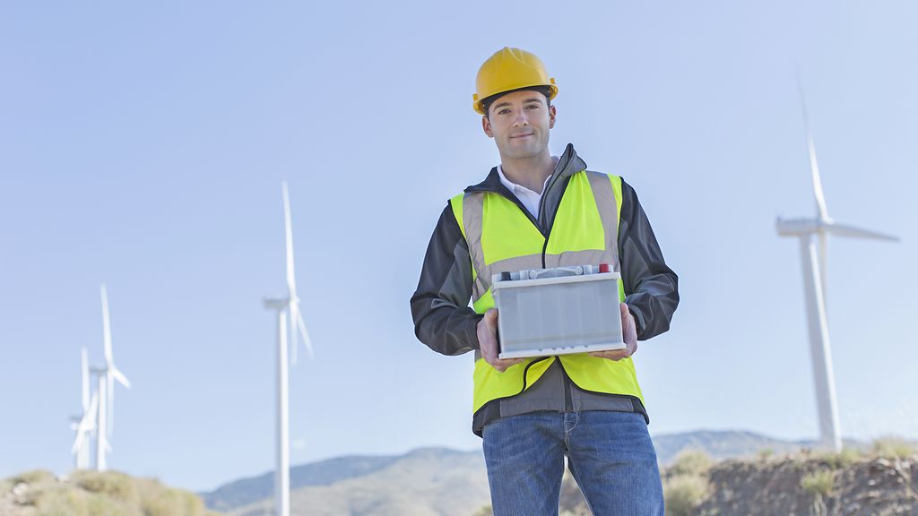 Worker with Battery in front of wind turbines