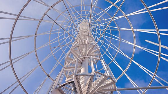 Telephone communication tower with spiral staircase photographed against the blue sky.