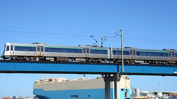 Zug fährt über eine Brücke vor dem Hintergrund eines Hafens