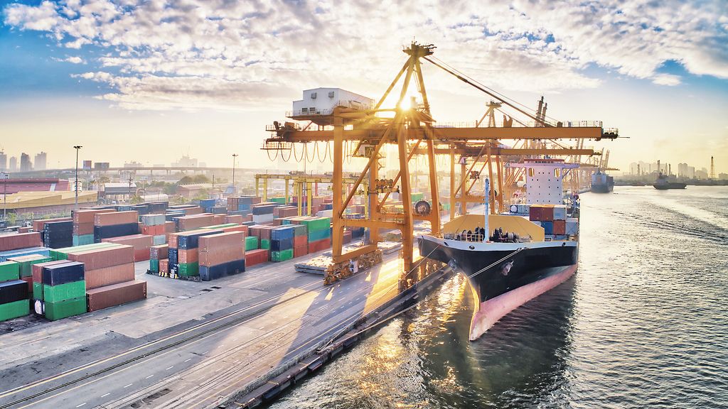 Aerial view of business port with Shore crane loading containers in freight ship. Container ship in import export and business logistics with crane and Shipping cargo. International transportation and Business logistics concept. | © GettyImages/chain45154