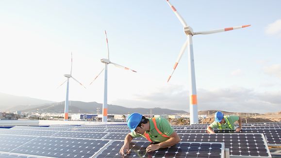 Bild von Arbeitern, die Sonnenkollektoren bei einem Plan für erneuerbare Energien inspizieren.|© Getty Images/LL28