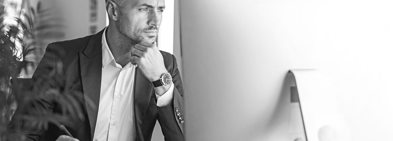 Image of confident businessman 30s wearing suit working in office and looking on computer ©Drobot Dean - stock.adobe.com