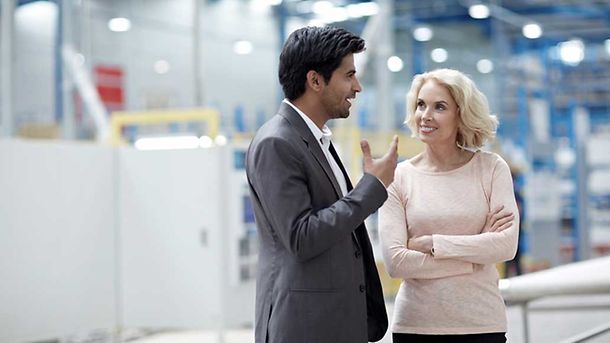 Young businessman having a conversation with senior female colleague at factory shopfloor