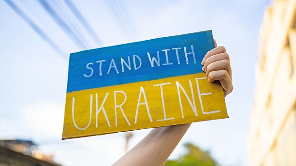 Demonstrator holding "Stand with Ukraine" placard 