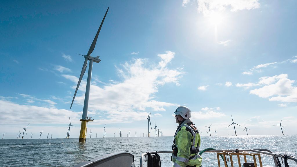 Arbeiter blickt vom Schiff zum Offshore-Windpark