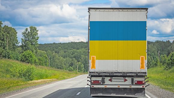 A truck with the national flag of Ukraine depicted on the back door carries goods to another country along the highway. Concept of export-import,transportation, national delivery of goods