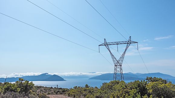 Panoramic landscape of Lefkada island coast in Greece with green woods, blue sky and electrical support line. Summer travel