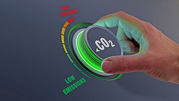 Lower CO2 emissions to limit global warming and climate change. Concept with manager hand turning knob to reduce levels of CO2. New technology to decarbonize industry, energy and transport