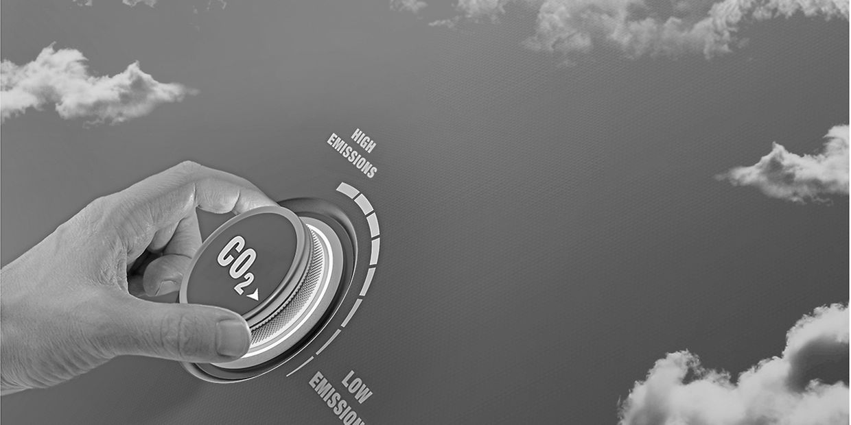 Lower CO2 emissions to limit global warming and climate change. Concept with manager hand turning knob to reduce levels of CO2. New technology to decarbonize industry, energy and transport